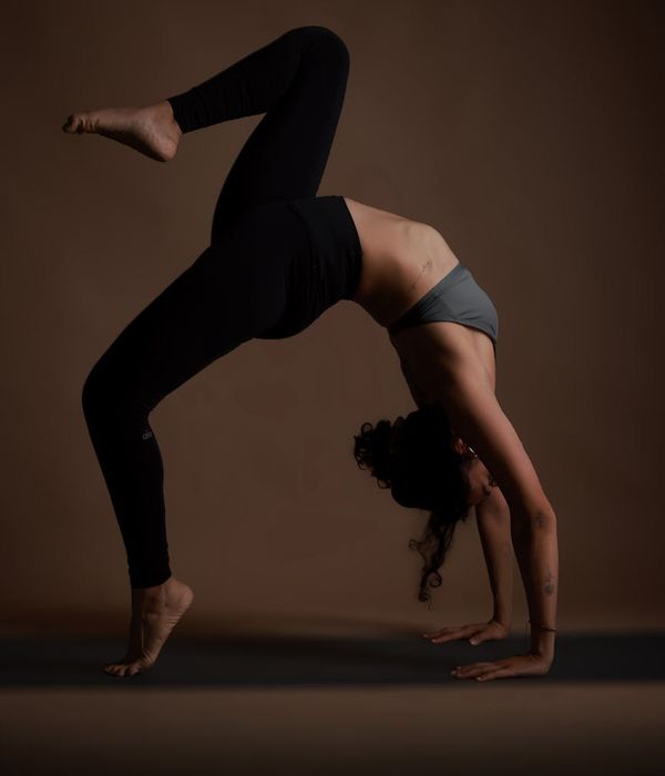 Woman practicing yoga balance pose in dark room with lime light